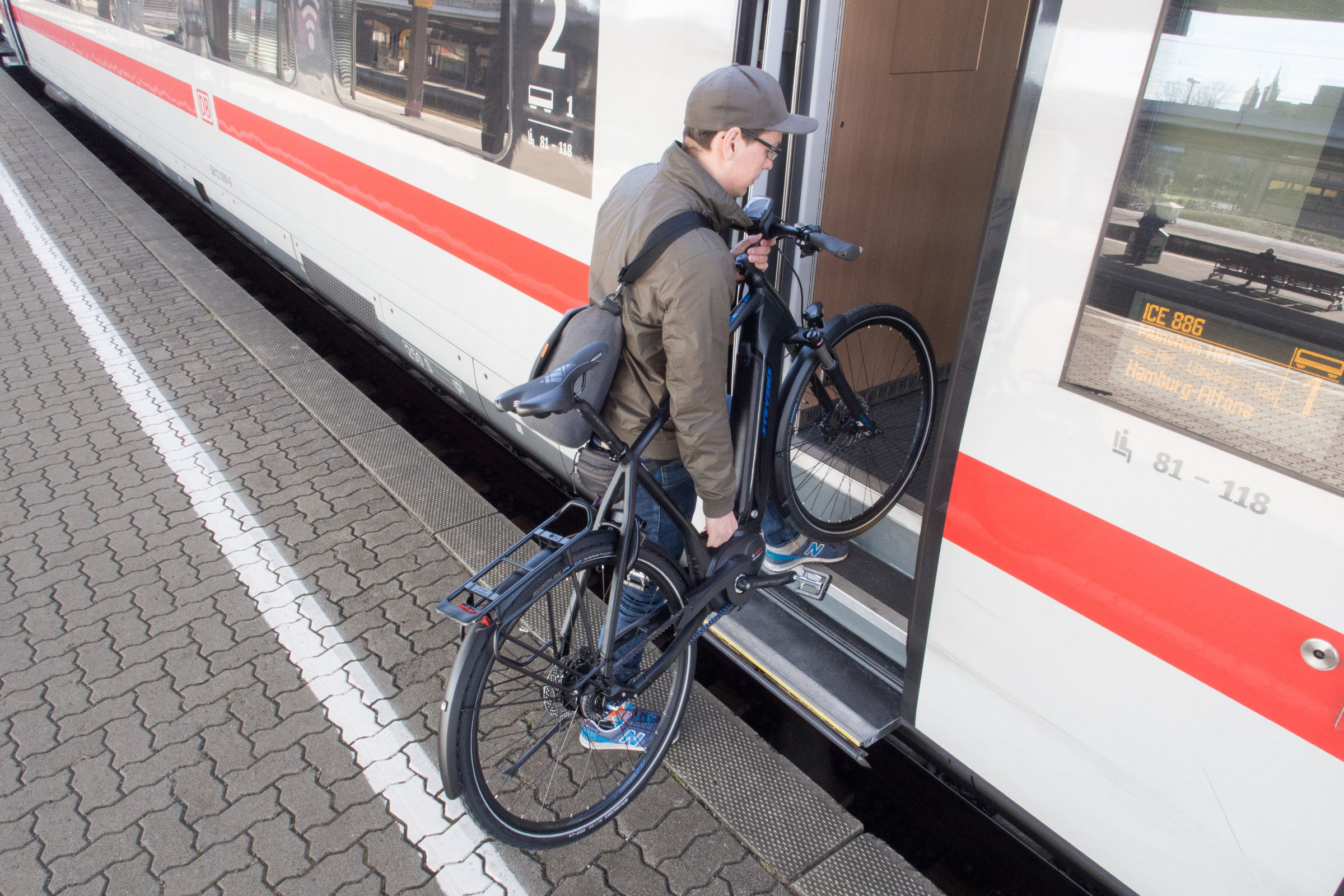 Mann steigt mit Fahrrad in Zug der Deutschen Bahn