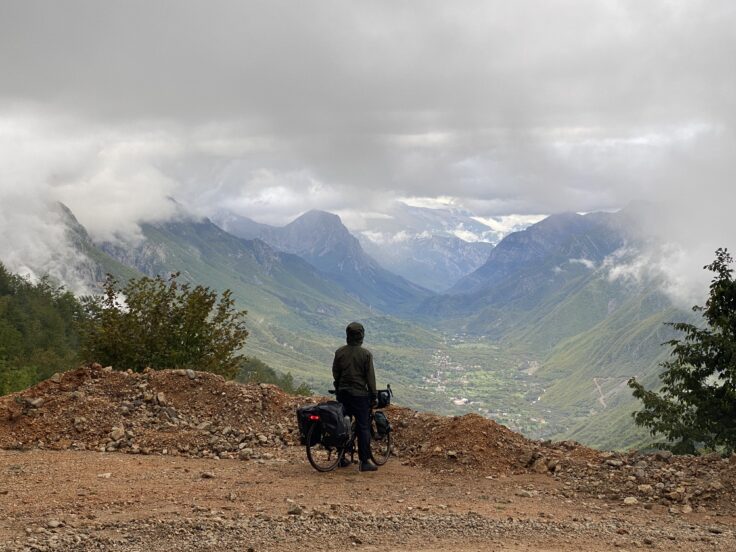 Radreisende Person blickt auf bewaldetes Tal