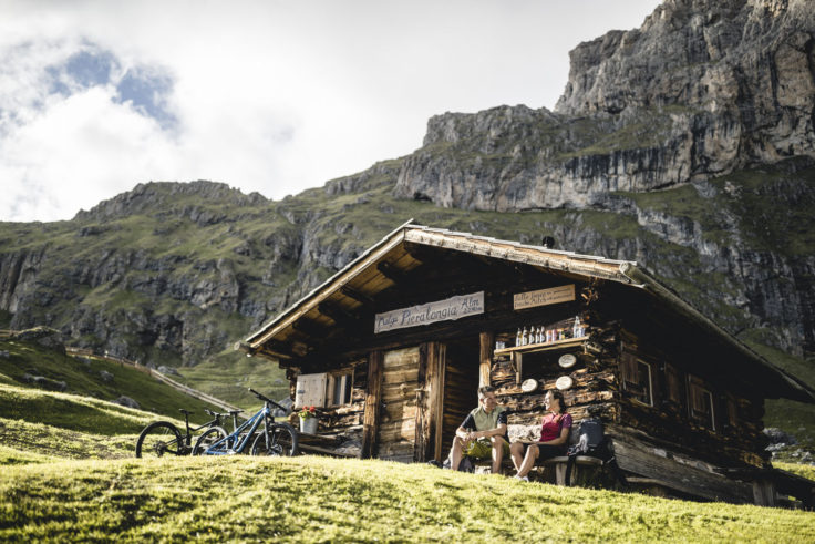 Mountainbiker sitzen vor einer Almhütte in den Dolomiten