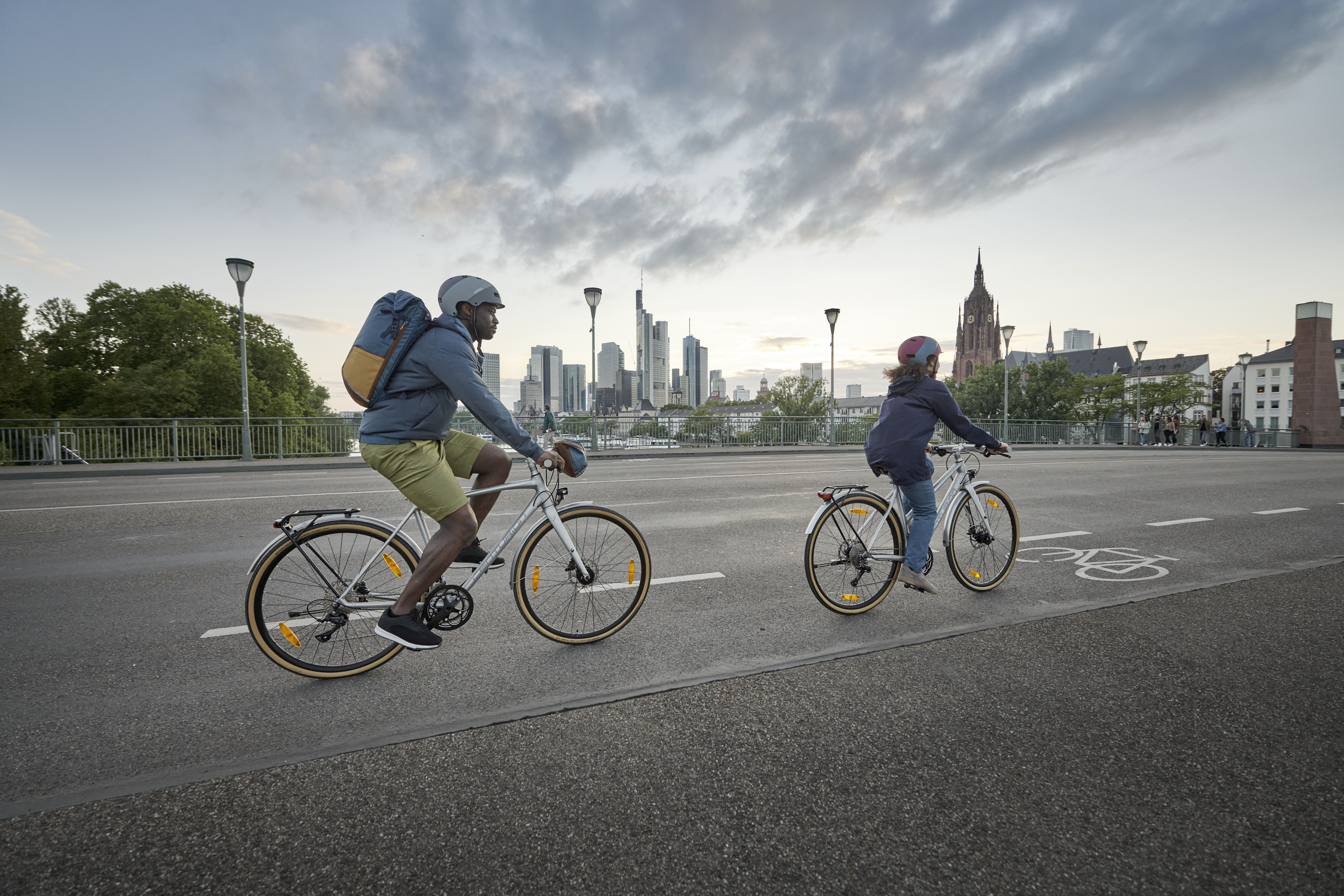 Zwei Radfahrer pendeln im Alltag vor Stadtkulisse