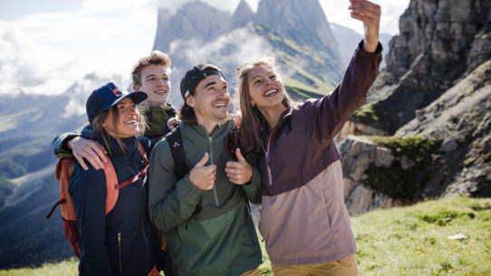 Eine Gruppe junger Wanderer mit Selfie vor Bergkulisse in den Dolomiten