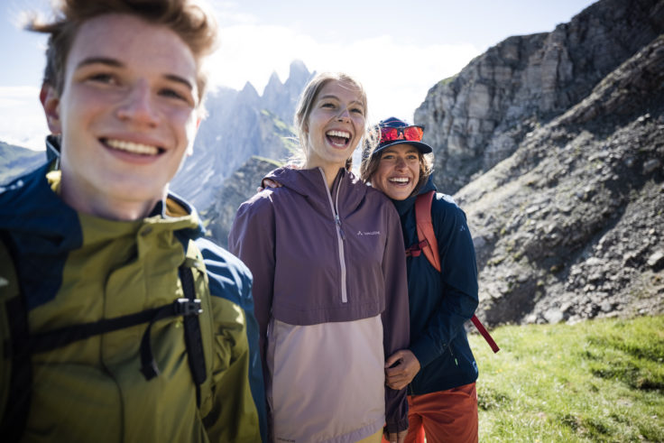 3 Jugendliche lachen in die Kamera vor Bergkulisse